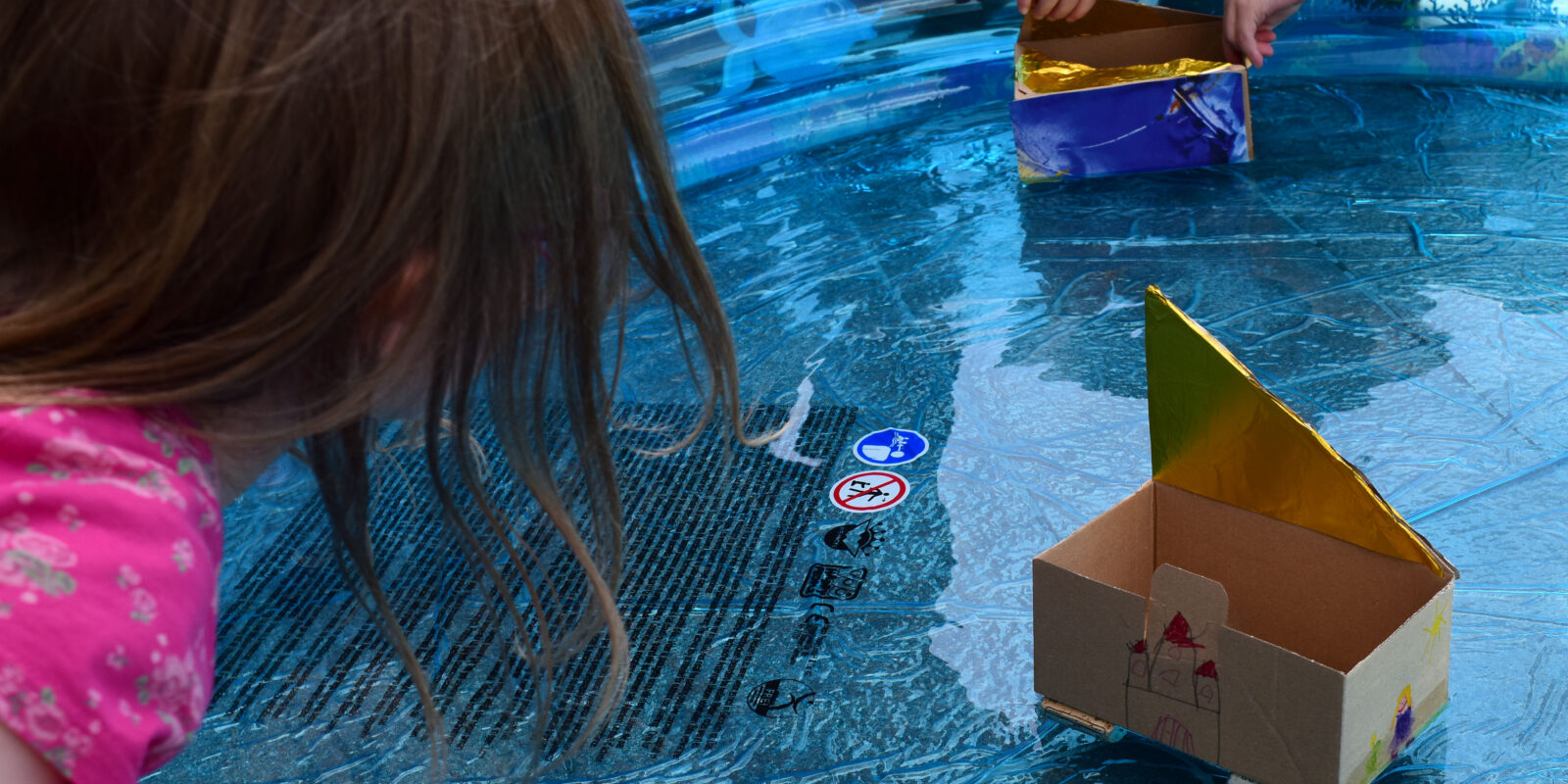 Kinder spielen mit selbstgebauten Booten auf dem Wasser