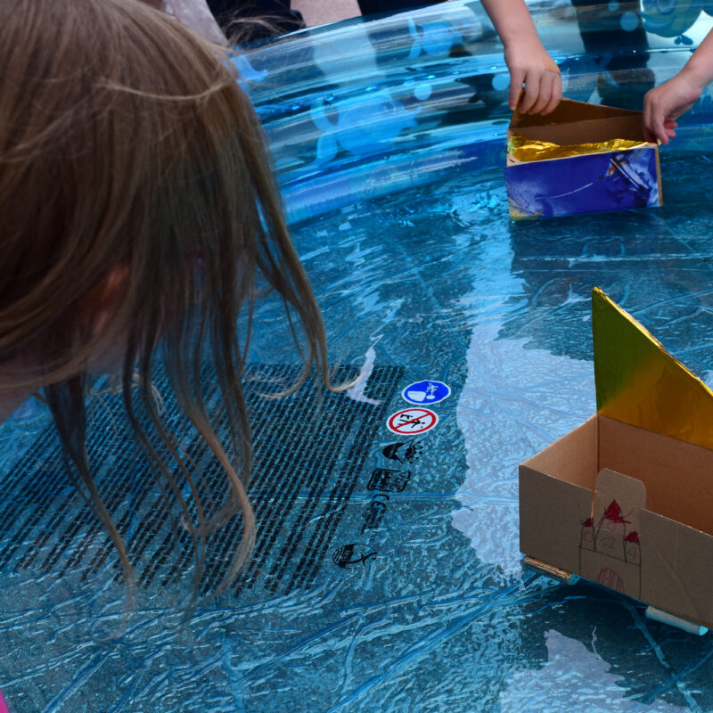 Kinder spielen mit selbstgebauten Booten auf dem Wasser