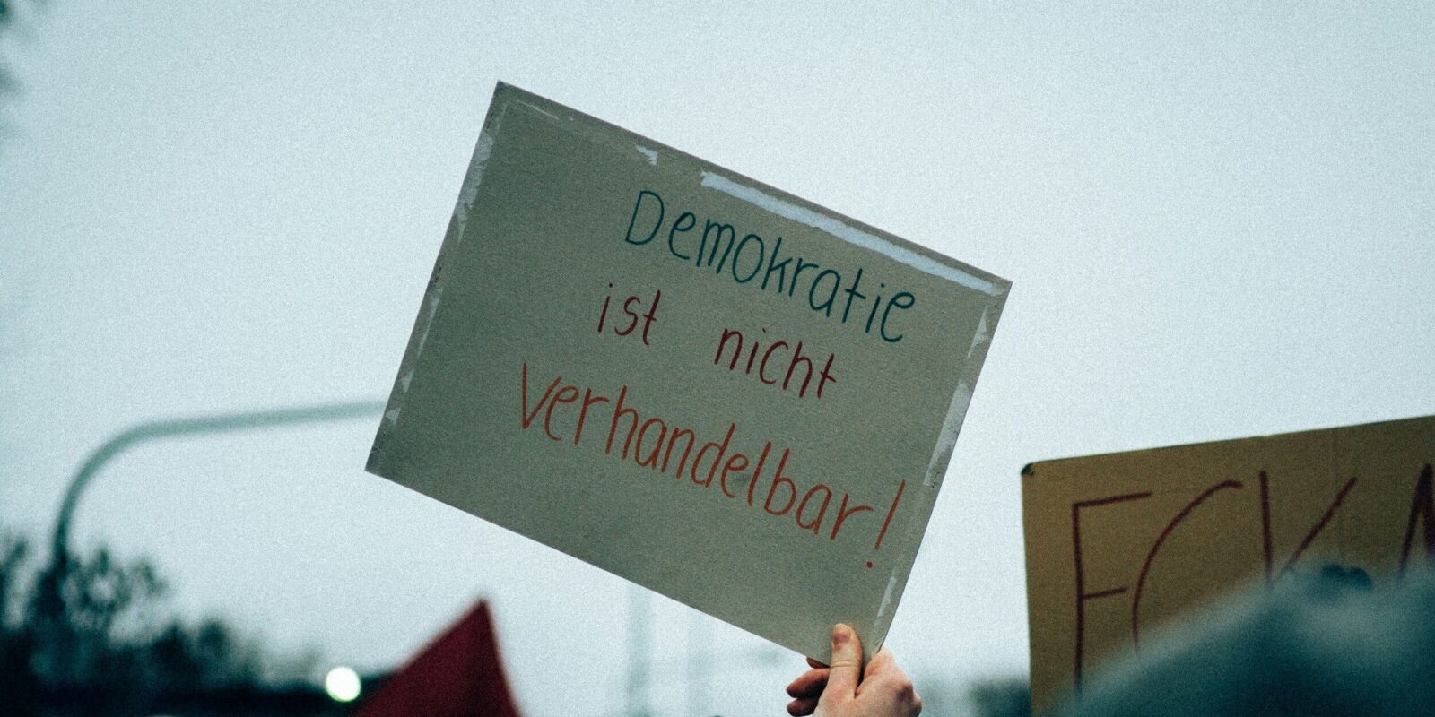Ein Schild in einer Hand auf dem steht "Demokratie ist nicht verhandelbar"