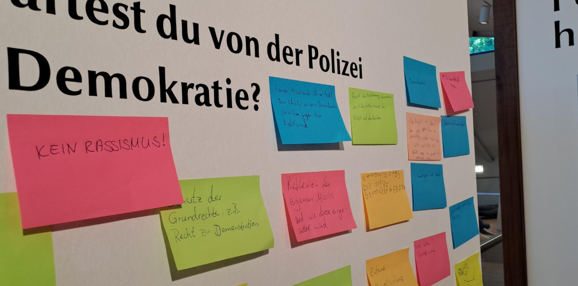 Eine Wand mit kleinen bunten Zetteln mit Handschrift