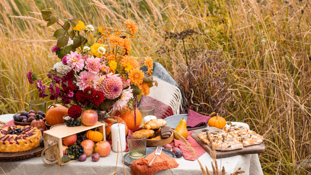 Tisch mit Kürbis, Brot und Blumen zu Erntedank im Kornfeld