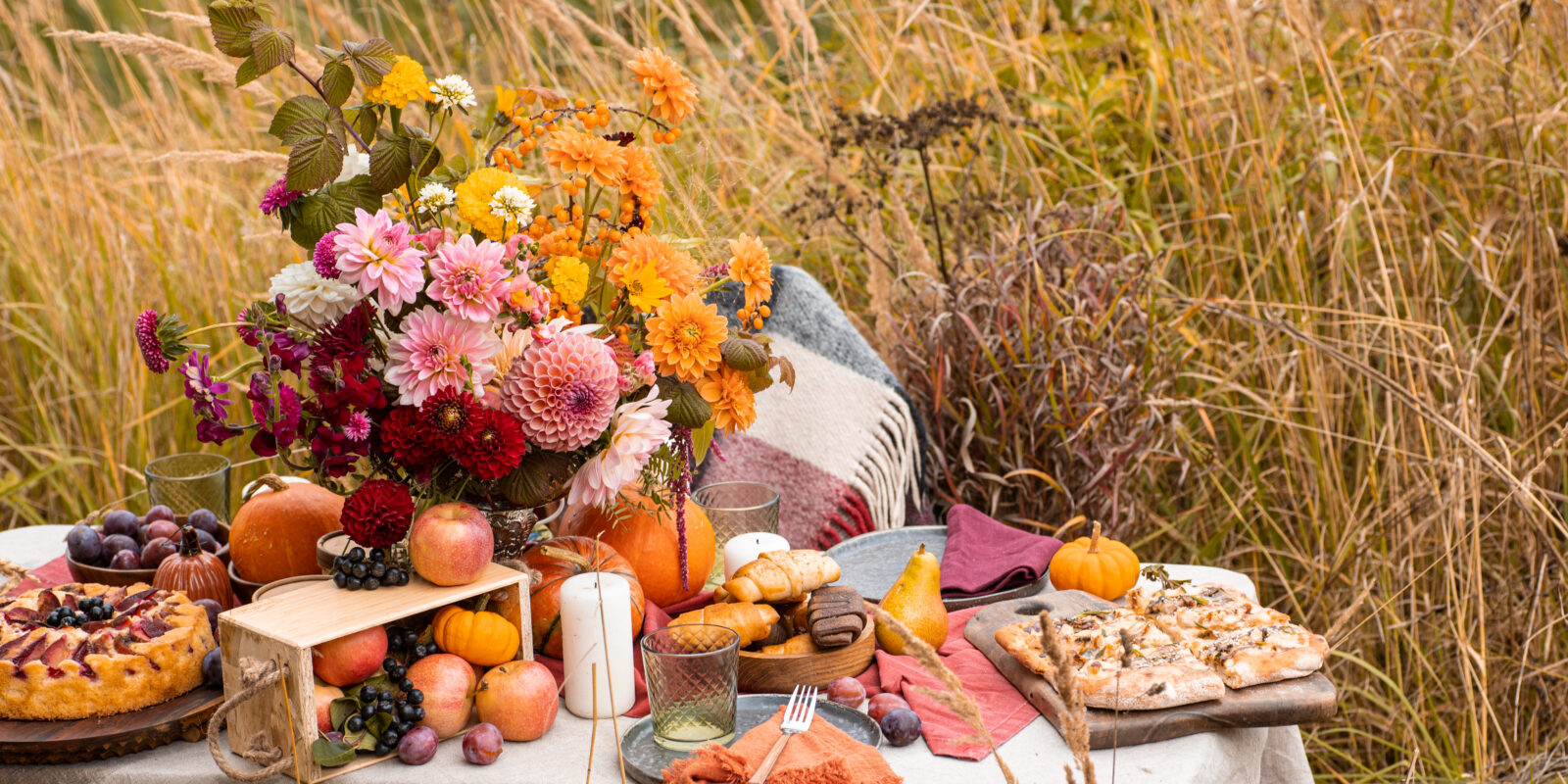Tisch mit Kürbis, Brot und Blumen zu Erntedank im Kornfeld