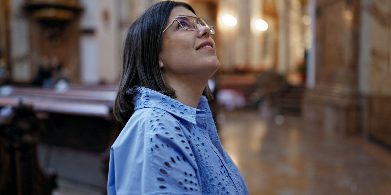 Frau in Kirche mit Brille schaut sich um
