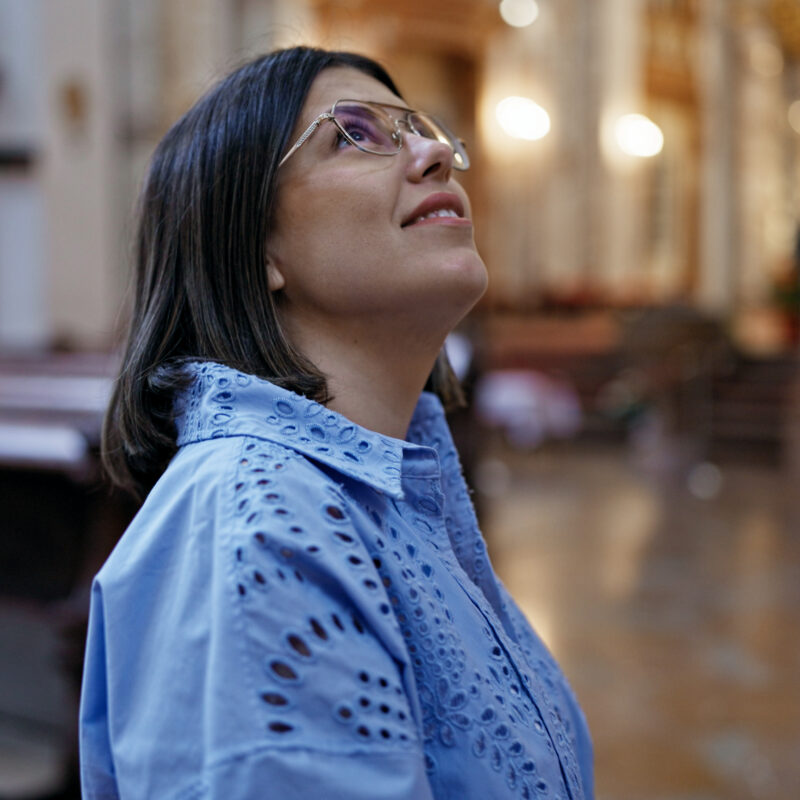 Frau in Kirche mit Brille schaut sich um