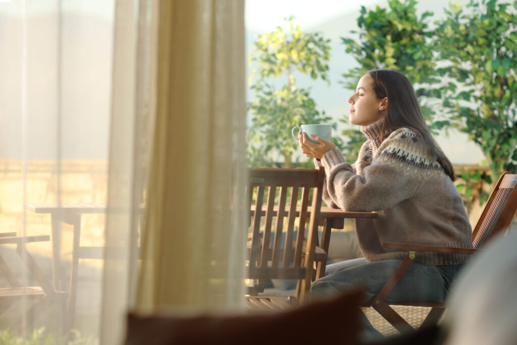 Frau sitzt vor dem Fenster mit einer Tasse Kaffee